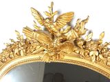 a mirror that has a gold frame with a bird and flowers on it