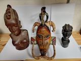 three african masks are sitting on a table next to a vase
