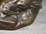 a bronze statue of a person laying on a rock