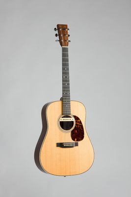 un gros plan d'une guitare acoustique sur fond gris