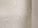 a close up of a white pillow with embroidered flowers on it