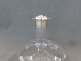 une bouteille en verre transparent avec un bouchon argenté posée sur une table