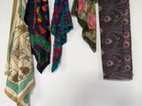 several different colored scarves hanging on a white wall in a room