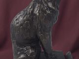 statue of a dog sitting on a wooden base on a red background