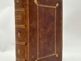 an old brown book with gold trim sitting on top of a white surface
