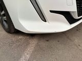 the front end of a white car with a black bumper