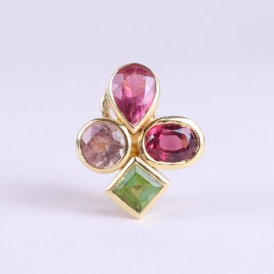 un gros plan d'une bague rose et verte posée sur une surface blanche