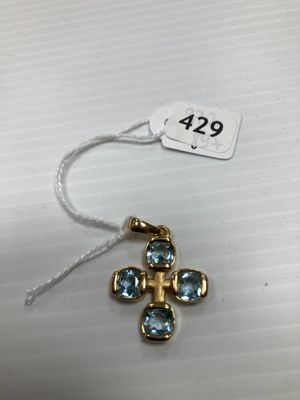 un pendentif en forme de croix en or orné de cristaux bleus, monté sur un cordon