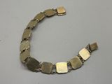 a close up of a metal bracelet on a white surface