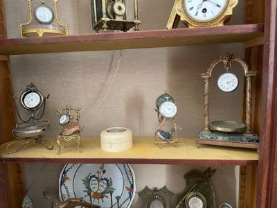 de nombreuses horloges différentes posées sur une étagère dans la pièce