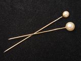 une paire d'épingles en perles et en or sur fond noir