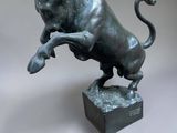 bronze statue of a bull on a pedestal on a gray background