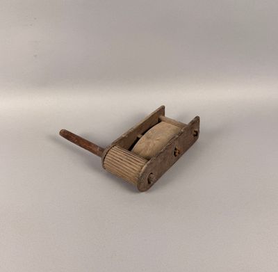 un vieux porte-brosse de toilettes en bois, muni d'un manche en bois, posé sur une surface blanche