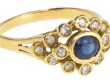 gros plan d'une bague en or avec une pierre bleue et des diamants