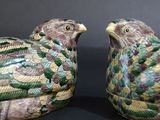 two ceramic birds sitting next to each other on a black surface