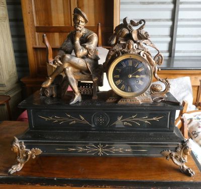 une statue représentant un homme assis sur une table, avec une horloge