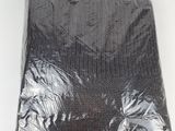 un gros plan sur un sac contenant des vêtements noirs posé sur une surface blanche