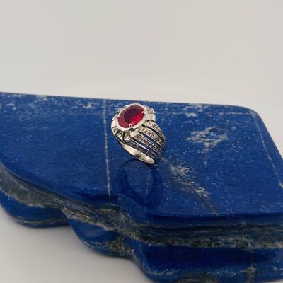 a close up of a ring with a red stone on a blue stone