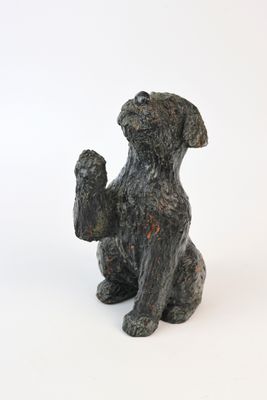 une statue représentant un chien assis sur une surface blanche