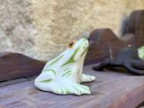a small frog sitting on a wooden bench next to a stone wall