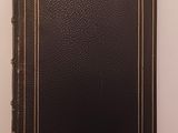 a black book with gold trim sitting on top of a white table