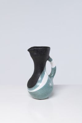 un vase noir et bleu posé sur une table blanche