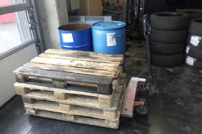 une palette sur laquelle sont posés deux fûts bleus, dans un garage