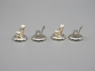 four pieces of silver metal are sitting on a white surface