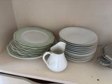 several plates and cups are stacked on a shelf in a kitchen