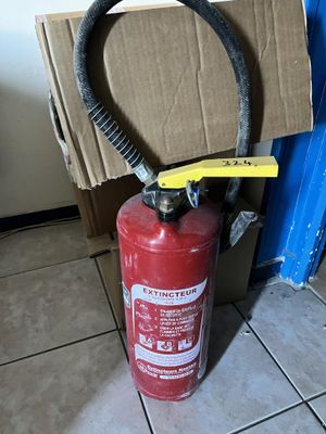 a fire extinguisor sitting on the floor next to a cardboard box