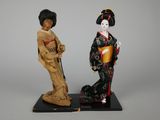 two figurines of women dressed in traditional japanese clothing stand on a black base
