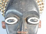 a close up of a wooden mask with a hat on it