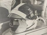 photographie en noir et blanc d'un homme dans une voiture de course, portant un casque