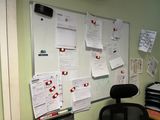 a black chair in front of a white board with papers on it