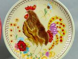 two plates with a rooster painted on them on a table