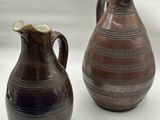 deux vases bruns posés l'un à côté de l'autre sur une surface blanche