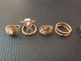 three rings and a ring with a bird on it sitting on a leather surface