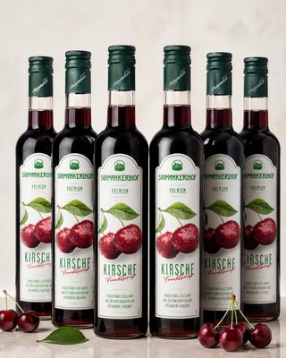 four bottles of red wine with cherries on a table