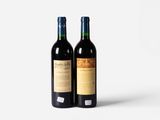 two bottles of red wine sitting next to each other on a white surface