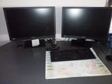 two computer monitors and a keyboard on a desk