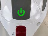 a white toilet with a green button on the side of it