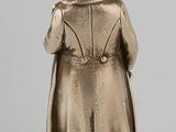 an antique silver figurine of a man in a trench coat and hat
