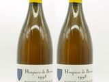 two bottles of white wine sitting next to each other on a white surface