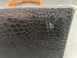 a black purse with orange handles sitting on a table