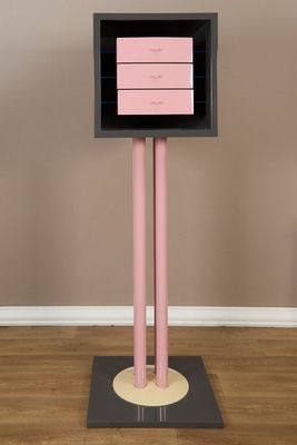 a pink and black cabinet on a pedestal in a room