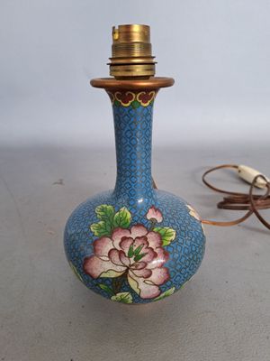 a blue vase with a flower on it next to a cord