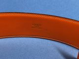 an orange leather belt with a metal buckle on a blue surface