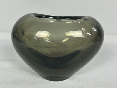 un vase en verre vert posé sur une surface blanche