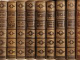 several old books are lined up in a row on a shelf