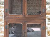 une armoire en bois avec des portes vitrées devant un mur en pierre